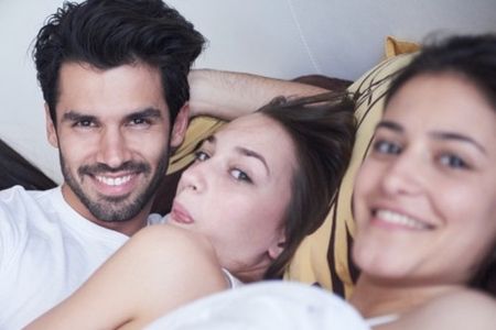 pareja joven en la cama con mujer joven